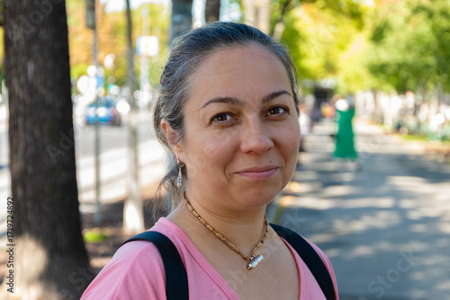 A 40-45-year-old woman in casual clothes with a backpack on her shoulders.