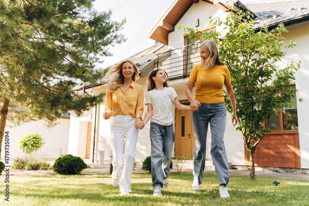 Obraz premium Happy family walking together in front of house beautiful mother grandmother and little girl