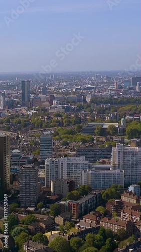 Vertical 4K drone video sweeps over South London’s Elephant & Castle, showcasing dense residential high-rises, leafy estates and a broad skyline that fades toward the Thames and distant City towers.