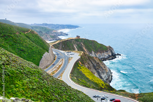 Scenic view of Highway 1 coastline from Gray Whale Cove Trail near Pacifica, California, with ocean waves, rugged cliffs, and lush green hills along the Pacific coast