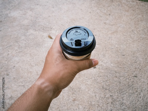 Hand holding a cup of coffee in disposable or take away packaging