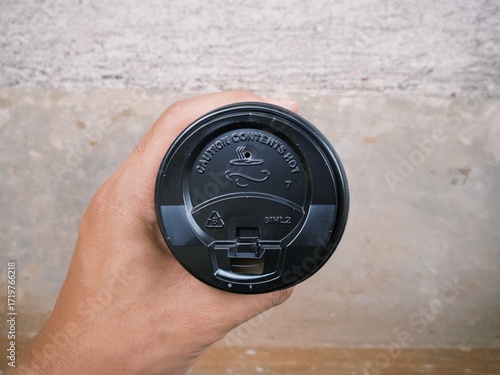 Hand holding a cup of coffee in disposable or take away packaging