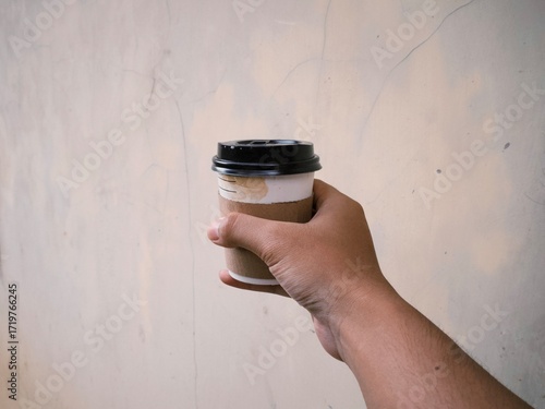 Hand holding a cup of coffee in disposable or take away packaging