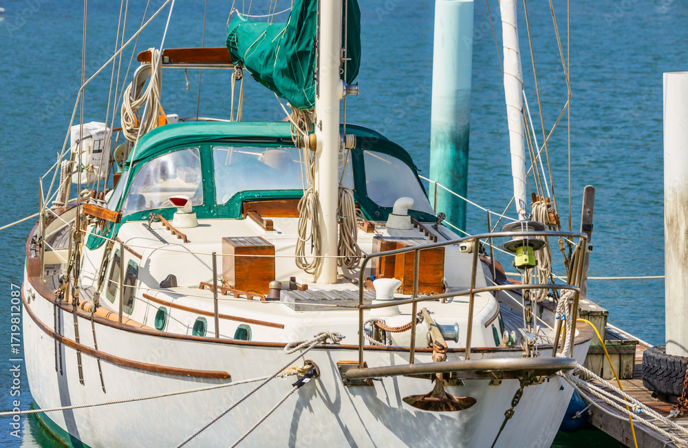 Obraz premium Classic sailboat with green canopy docked at marina. Elegant wooden details and nautical ropes highlight traditional craftsmanship. Peaceful harbor scene on a sunny day, symbolizing travel and