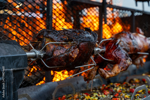 Obraz na płótnie Vue d’un cochon entier cuit à la broche lors d’une préparation traditionnelle, illustrant une cuisson lente en extérieur avec une présentation conviviale