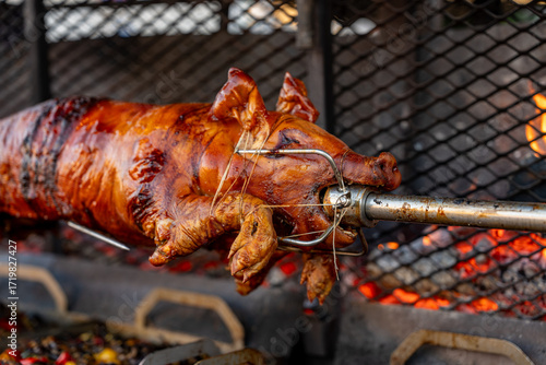 Fotografie Vue d’un cochon entier cuit à la broche lors d’une préparation traditionnelle, illustrant une cuisson lente en extérieur avec une présentation conviviale