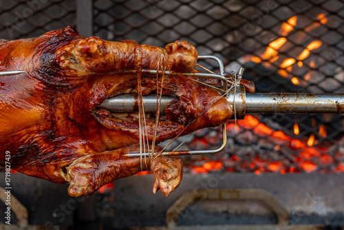 Quadro su tela Vue d’un cochon entier cuit à la broche lors d’une préparation traditionnelle, illustrant une cuisson lente en extérieur avec une présentation conviviale