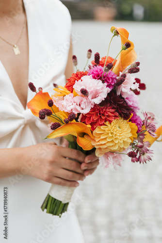moden bride holding bouquet of colorful flowers (mostly pink and orange)
