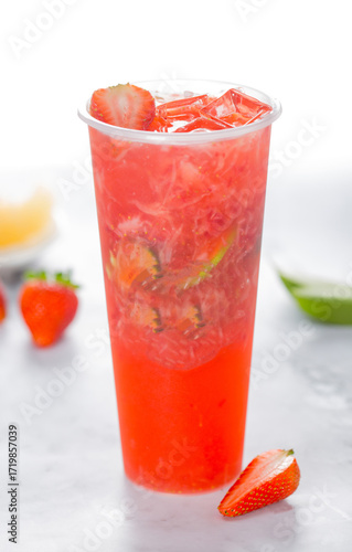 Refreshing strawberry drink in tall glass with ice and fresh fruit garnish