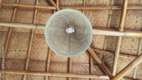 A decorative lamp crafted from woven rattan, casting warm light through natural patterns and showcasing elegant handmade craftsmanship.