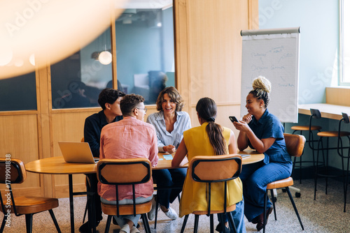 Bild auf Leinwand Group discussing ideas in a bright office setting around a table