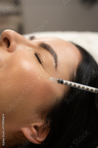 Close-up of a woman receiving a cosmetic injection near the eye area. A syringe is applied to the skin for beauty treatment, anti-aging care, and wrinkle reduction, symbolizing modern aesthetics and