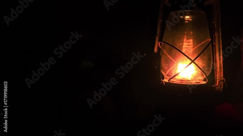 A calm, thoughtful Indian woman holds a glowing kerosene lantern in the warm darkness, her pensive expression evoking mystery, hope, and quiet strength as the soft light illuminates the night.