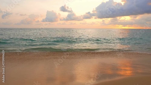 Golden sunset over the sea with gentle waves lapping on the sandy beach shore