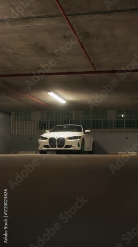 Cinematic reveal shot of a white luxury sports car parked in an underground garage. Dark shadows and fluorescent lighting create a cinematic mysterious atmosphere