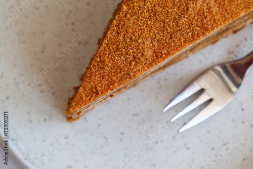 top view of  Slice of delicious layered caramel honey cake served on ceramic plate