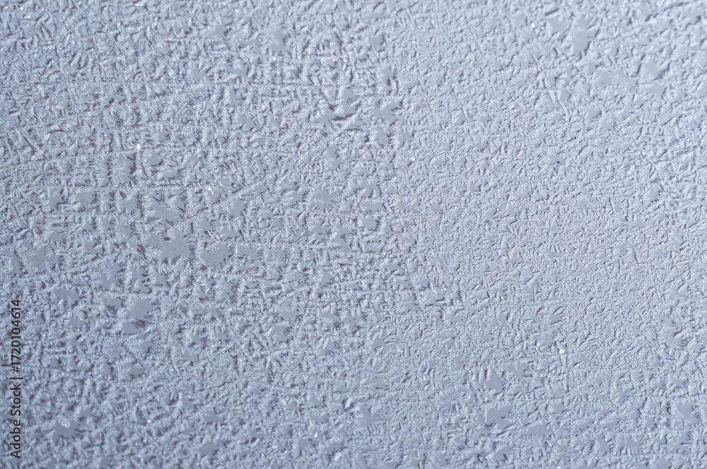 Obraz premium Close-up of delicate ice crystals forming intricate patterns on a window during a cold winter day.