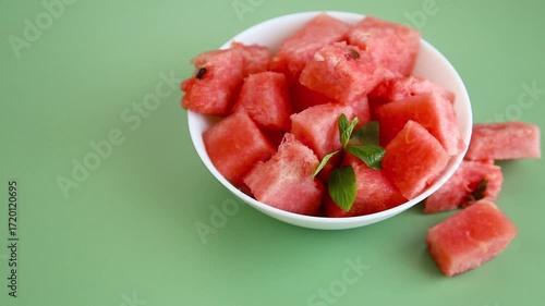 Bright watermelon cubes with green mint leaf in bowl