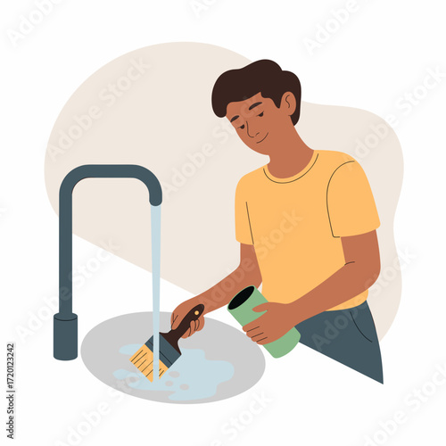 Young man cleaning paintbrush under running water in kitchen sink  