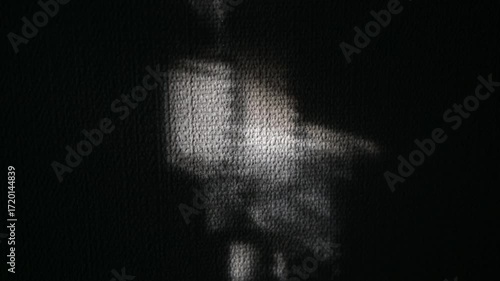 Abstract Shadow Play Grey Light Projection on Dark Fabric. Abstract shadow play video featuring a grey light projection cast onto dark fabric.