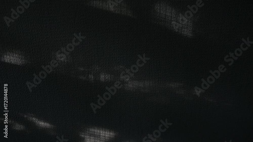 Abstract Shadow Play on Dark Surface. Abstract video featuring subtle light patterns and shadows cast upon a dark, textured surface. The grayscale palette and soft lighting create a moody atmosphere. 