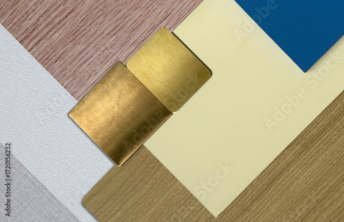 Interior design mood board. A mix of textures and materials, including natural wood veneer, brushed gold metallic, painted solid blue wood, cream laminated placed on wood and white fabric laminateds.
