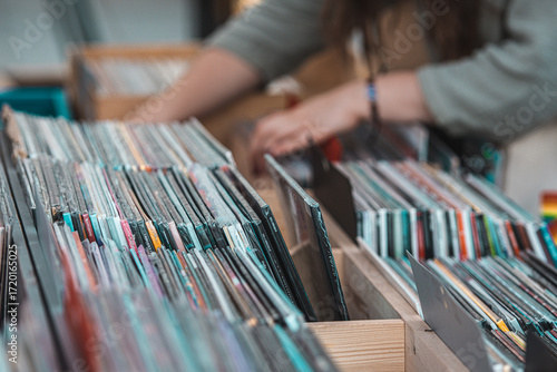 Girl browsing vinyl records in wooden crates at a music store or flea market. Close-up of hands flipping through vintage LP albums, symbolizing retro music culture, nostalgia and collecting
