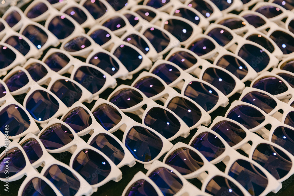 Fototapeta premium Large collection of stylish white sunglasses displayed in a market setting under bright lighting