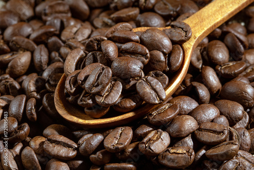 Close-up shot of a wooden spoon filled with fresh coffee beans