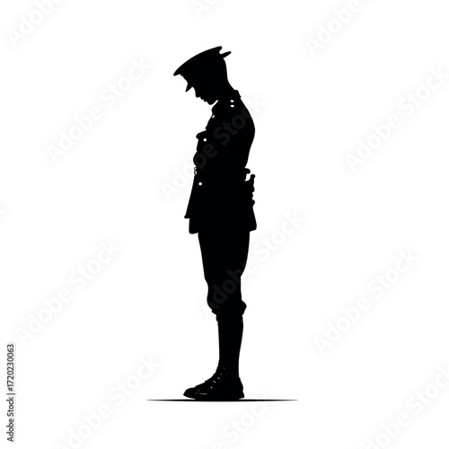Soldier standing in silhouette with head bowed in respectful stance  