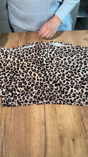 A woman unboxing and reviewing leopard print shorts. Vertical video..