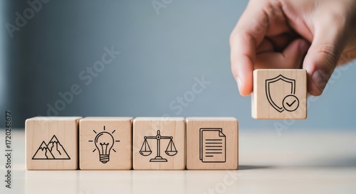 Hand placing wooden block with shield and checkmark symbol representing security and protection onto a row of blocks with icons