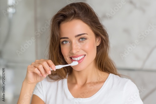 Happy young woman smiling while brushing her teeth for healthy oral care.