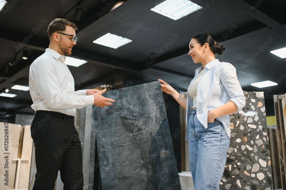 Naklejka premium Shop assistant showing ceramic tile to woman in store