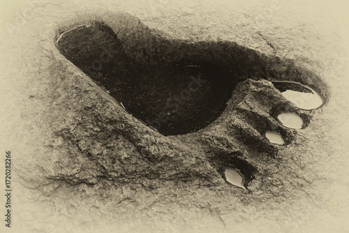 Footprint of a large human-like foot on granite stone, resembling the legendary Bigfoot track. Concept of mystery, mythology, and prehistoric presence.