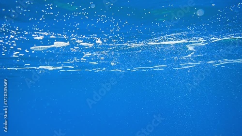 Light filtering down through blue water. Underwater sunlight in deep sea. Light viewed from blue abyss. Underwater sunlight shining deep with ripples on wave surface ocean ray, Under water Slow motion
