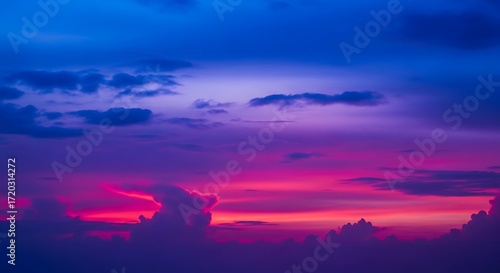 A vibrant sunset sky filled with dramatic hues of purple, pink, and orange, highlighting the clouds silhouettes against the colorful backdrop.