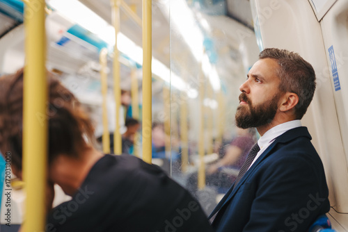 Wall Mural Side view of man sitting in subway train, travelling to work.