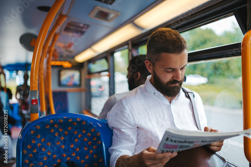 Canvas Print Man sitting in bus and reading newspapers, travelling to work.