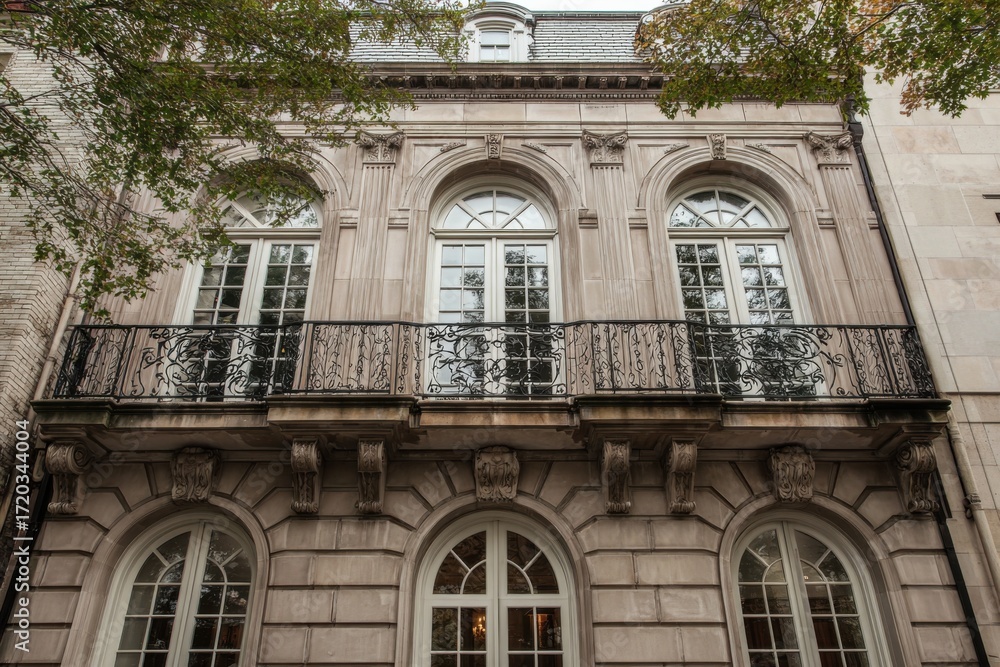 Obraz premium Elegant historic building with intricate balcony design located in a bustling city showcasing classic architecture and urban charm during late afternoon