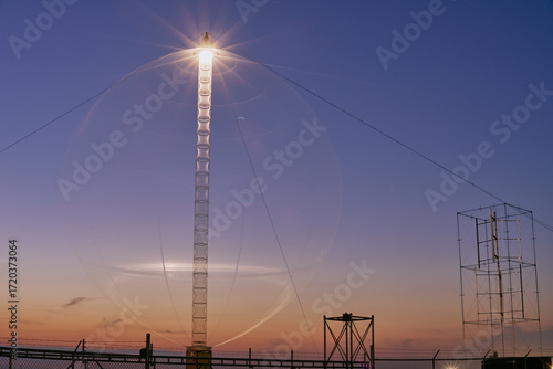Illuminated vertical axis wind turbine tower in Saskatchewan photographed at night with bright lights against a dark sky.