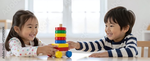 Two happy children playing with a colorful stacking toy at a table.
