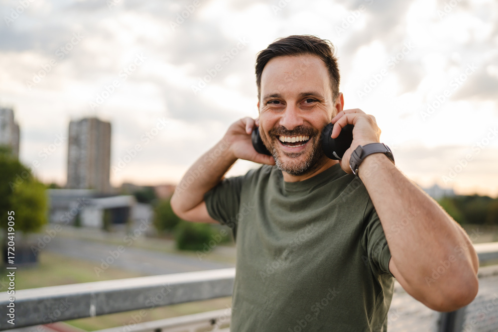 Naklejka premium Man enjoying music with headphones in urban setting