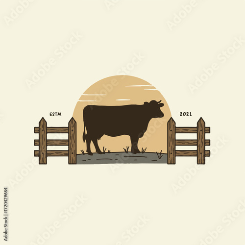 Silhouette of a cow in a pasture with a wooden fence