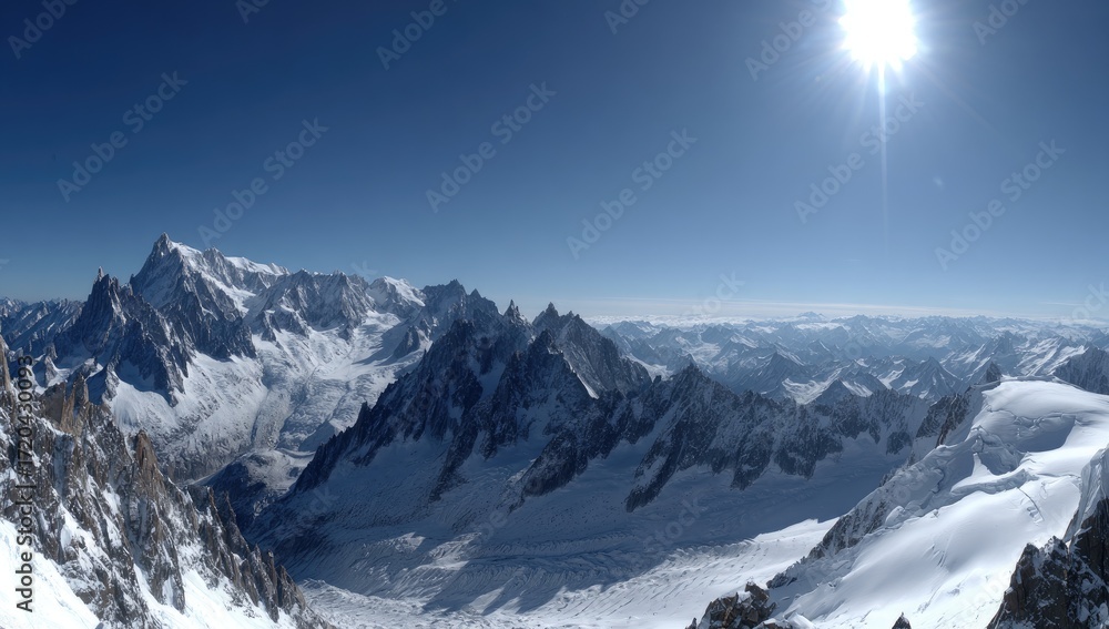 Obraz premium Expansive vista of snow-capped mountain peaks under a vibrant blue sky.