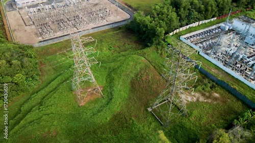 Aerial drone view of an electrical power substation surrounded by residential buildings and greenery.