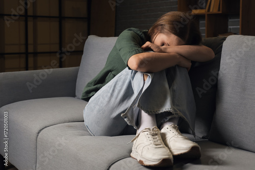 Young woman sitting on sofa...