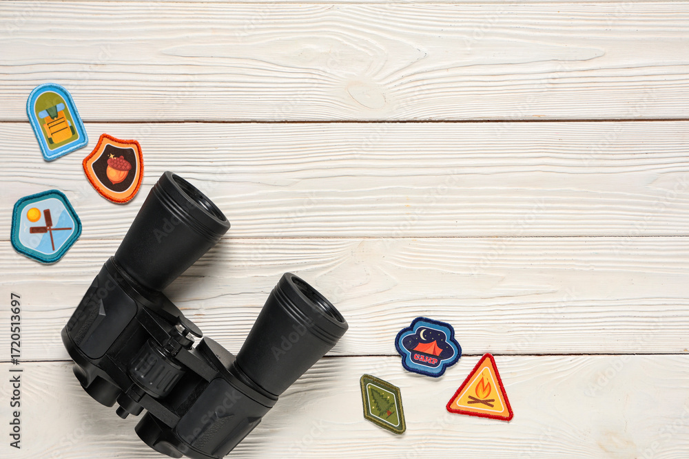 Naklejka premium Set of scout badges and binoculars on white wooden background with space for text