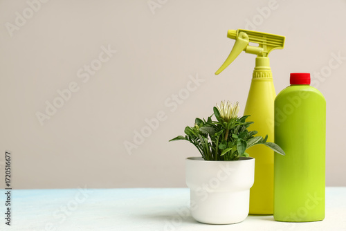 Bottle of plant fertilizer and sprayer on light background