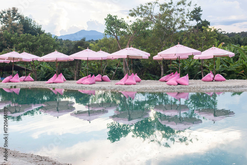 Pink umbrellas on the artificial sea behind are beautiful green mountains